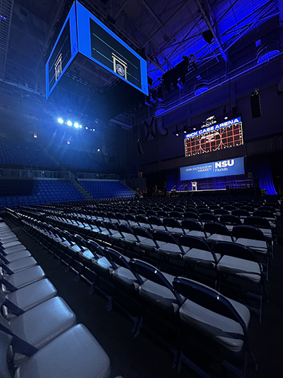 Wide angle of Rick Case Arena with rows of chairs before a stage